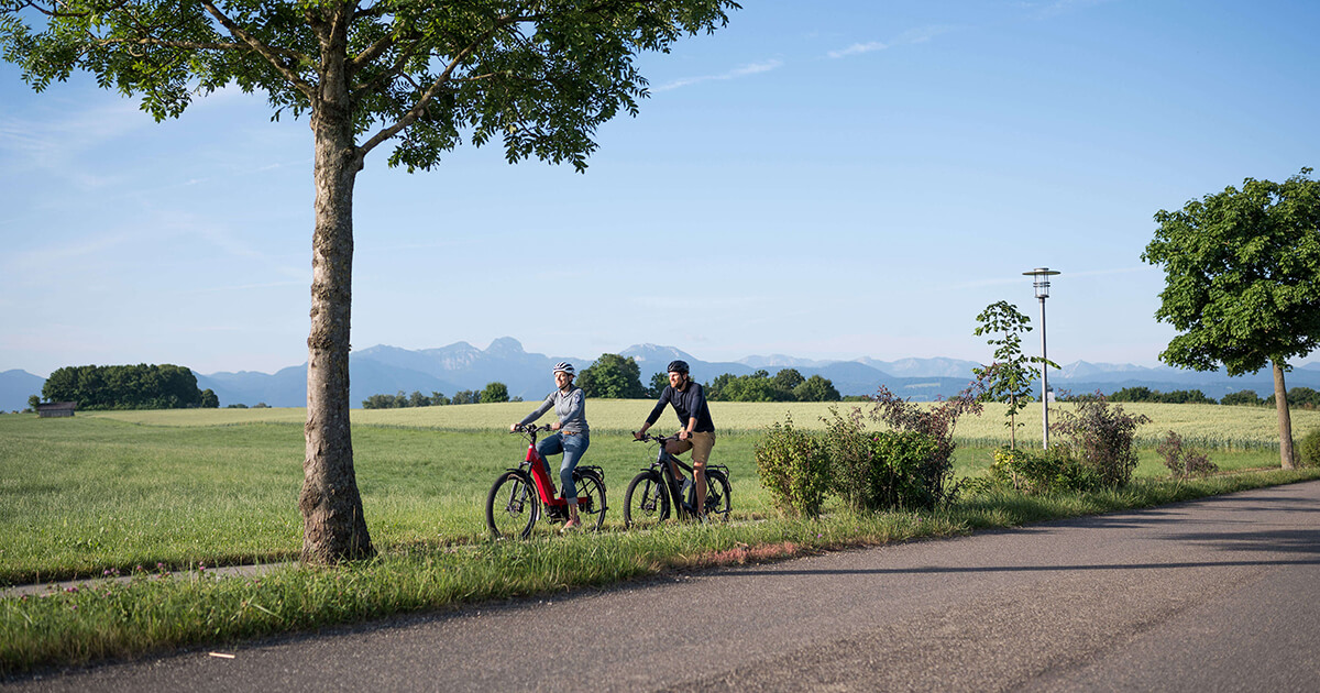 Pärchen fährt Fahrrad auf Radweg in Bad Aibling mit Alpenpanorama