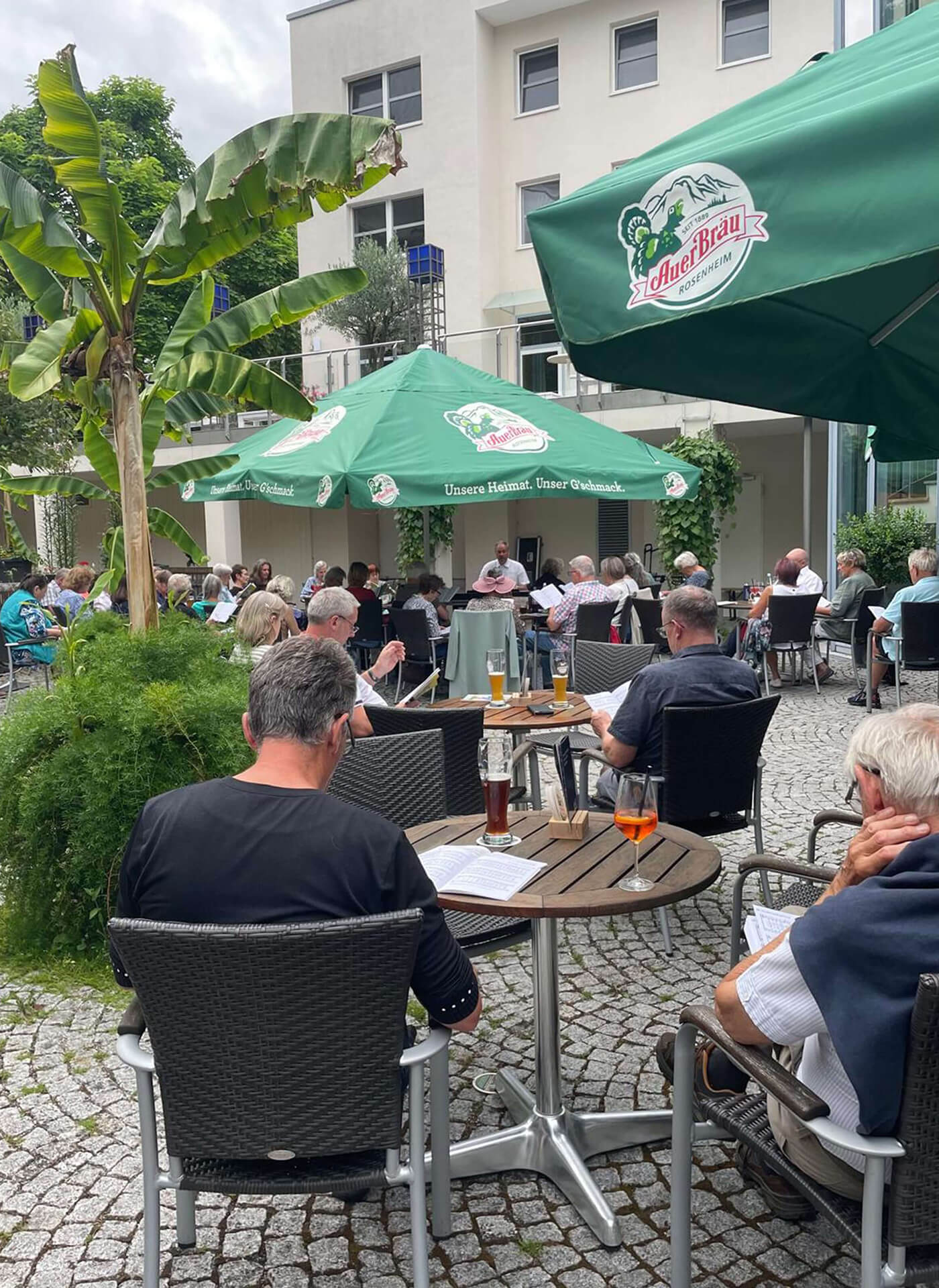 Menschen singen gemeinsam im Biergarten des Kurhauses Bad Aibling