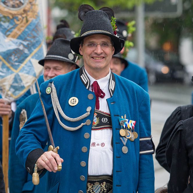 Schützenträger in Tracht und blauer Uniform, lächelnd in der Parade