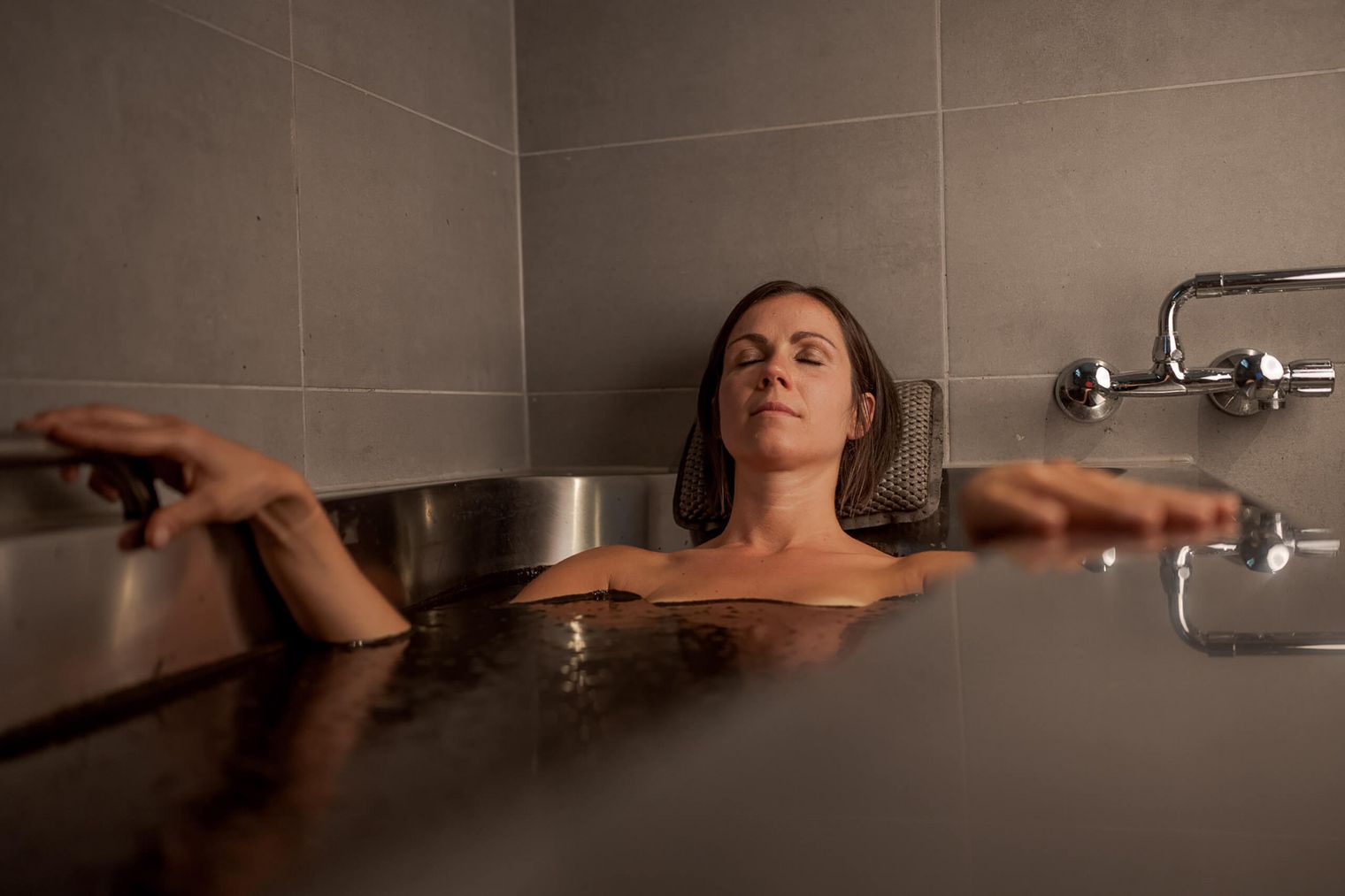 Frau entspannt sich in Moorbad, Wellness-Erlebnis mit geschlossenen Augen.