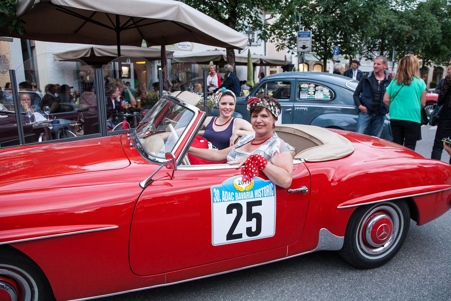 Zwei lächelnde Frauen in einem roten Oldtimer Cabrio bei der Oldie Night