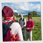 Kräuterexpertin erklärt Teilnehmergruppe Wissenswertes zu Wildkräutern am Wegesrand