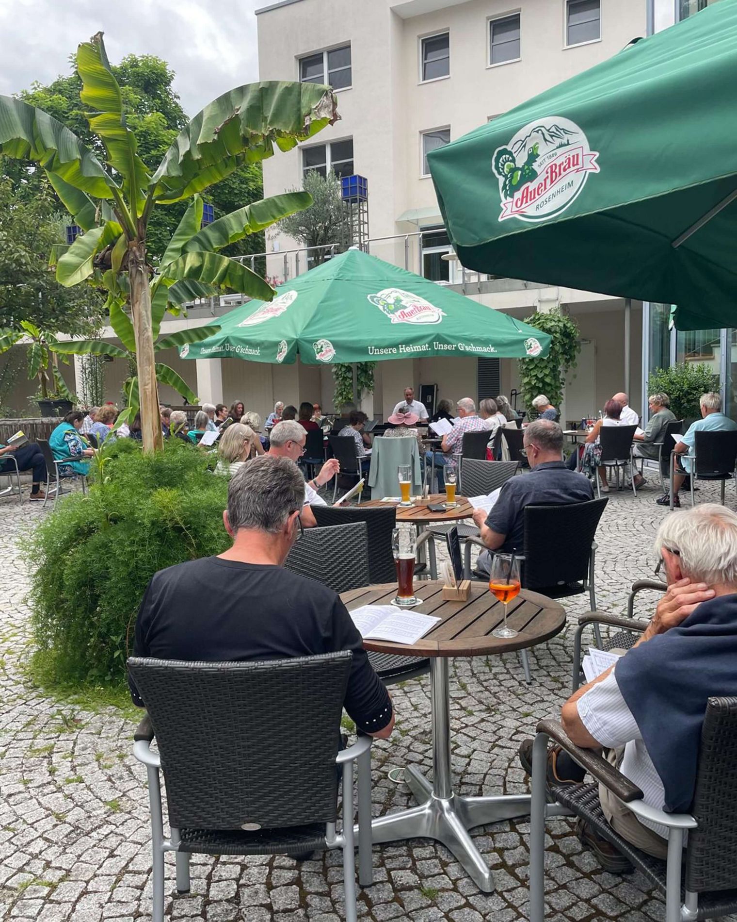 Menschen singen gemeinsam im Biergarten des Kurhauses Bad Aibling
