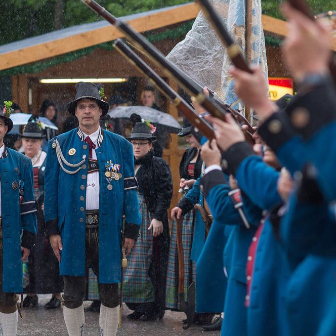 Schützen in blauen Uniformen bei einer Parade im Regen