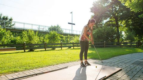 Junge Frau spielt Minigolf im Kurpark Bad Aibling